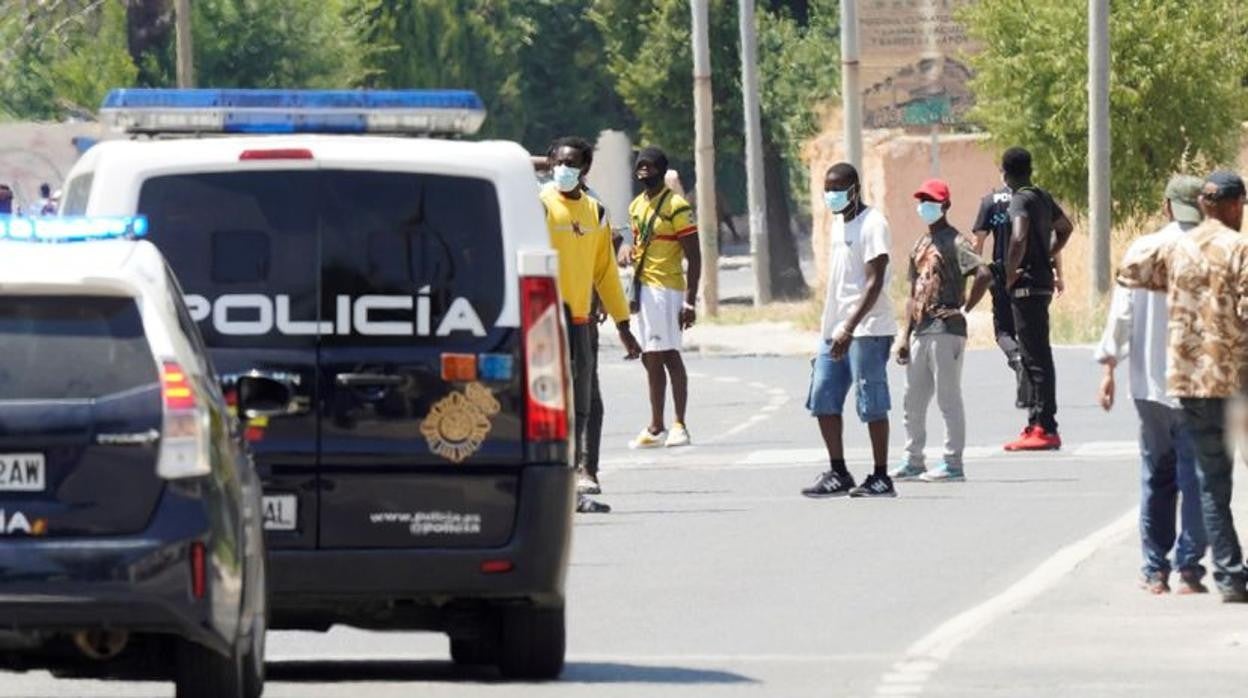 Vehículos de la Policía Nacional junto a los temporeros de Albacete