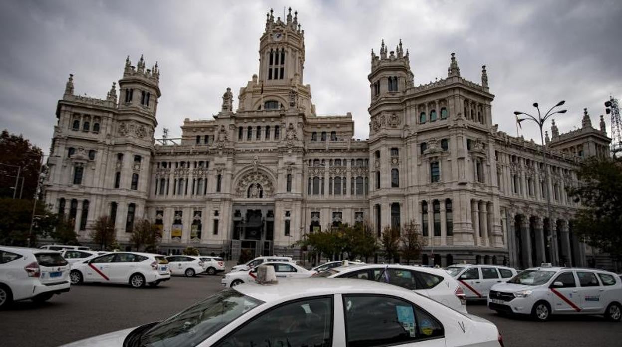 Un grupo de taxis circulan por la plaza de Cibeles frene a la sede del Ayuntamiento de Madrid