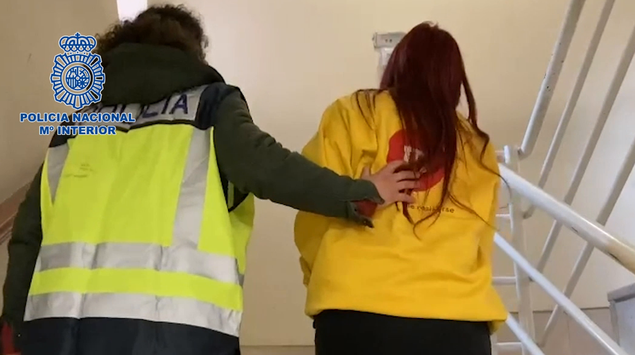 Una agente conduce a la detenida por dependencias policiales