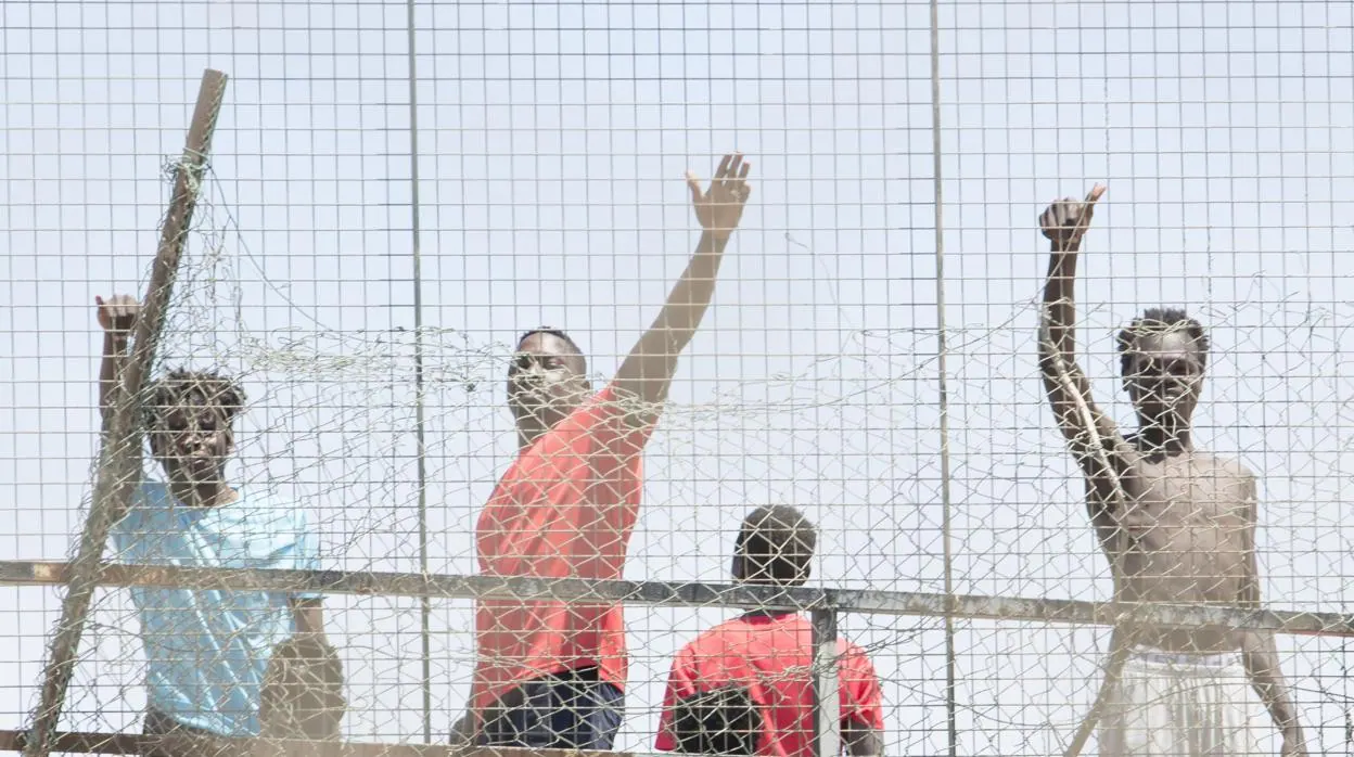 Varios inmigrantes detrás de una valla en la Ciudad del Fútbol del Altos del Real a 18 de mayo de 2021, en Melilla (España)