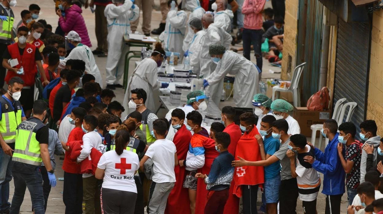 Migrantes esperan a ser atendidos por la Cruz Roja en Ceuta