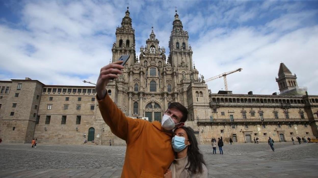 Dos turistas se fotografían ante la Catedral de Santiago