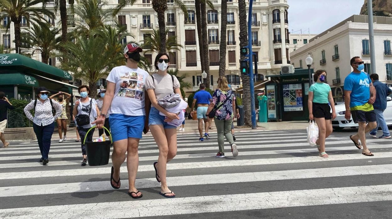 Imagen de personas con mascarilla por el coronavirus dirigiéndose a la playa en Alicante