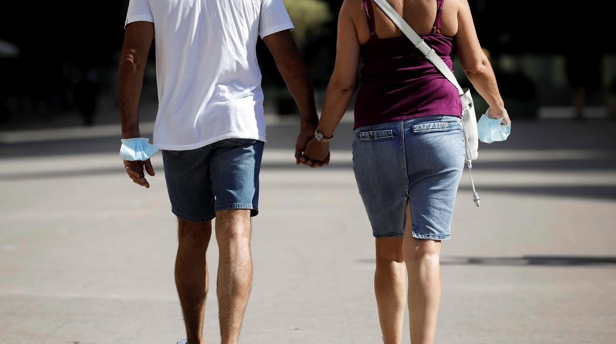 Una pareja con la mascarilla de la mano en Valladolid este sábado