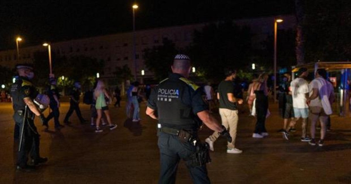 Agentes de la Guardia Urbana y jóvenes abandonando la playa de la Barceloneta