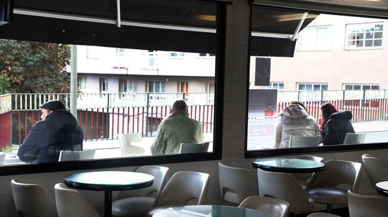 Una cafetería de Santiago con las mesas vacías en el interior y llenas en el exterior