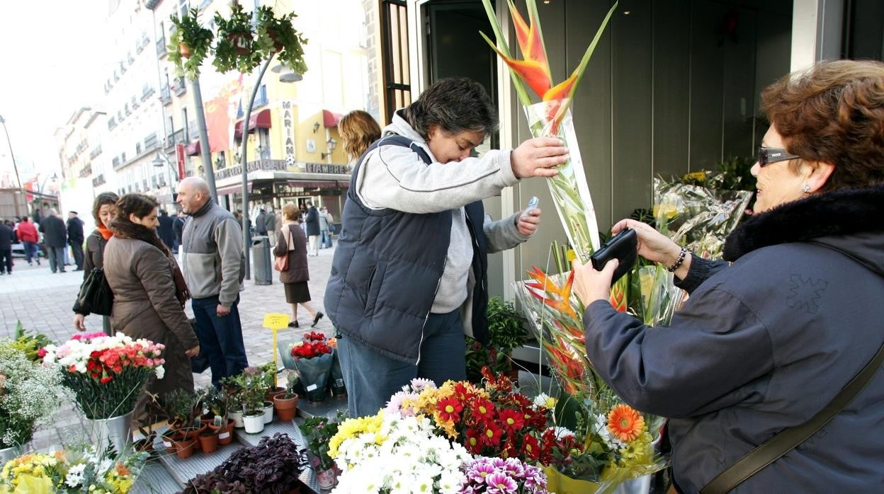 Una comerciente de los quioscos vende un ramo de flores a una mujer en Tirso de Molina