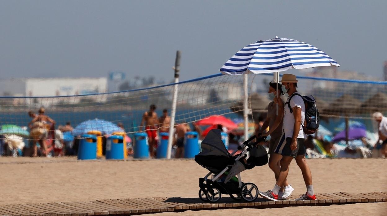 Imagen de personas protegiéndose del calor en la playa de la Malvarrosa de Valencia
