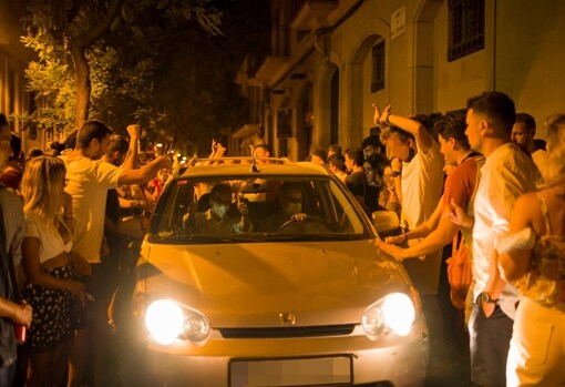 Decenas de personas rodean a un vehículo que circula por una calle del barrio de Gracia en plenas fiestas