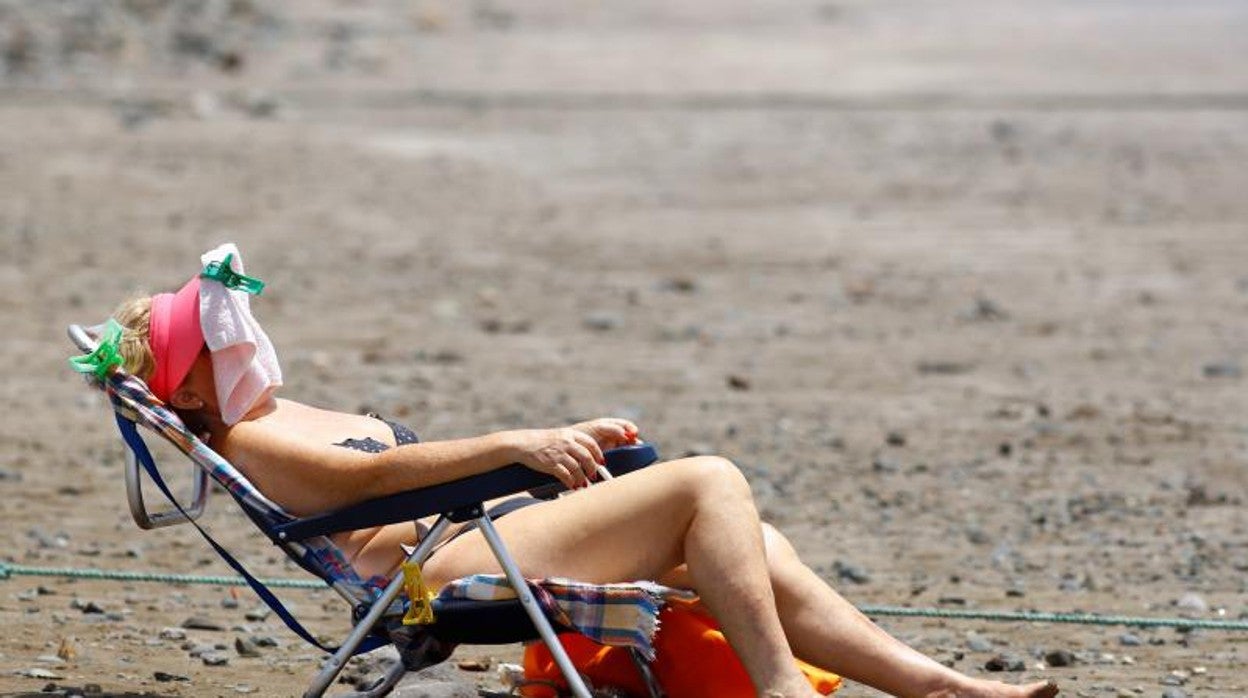 Una mujer toma el sol en la playa de Maspalomas, Gran Canaria