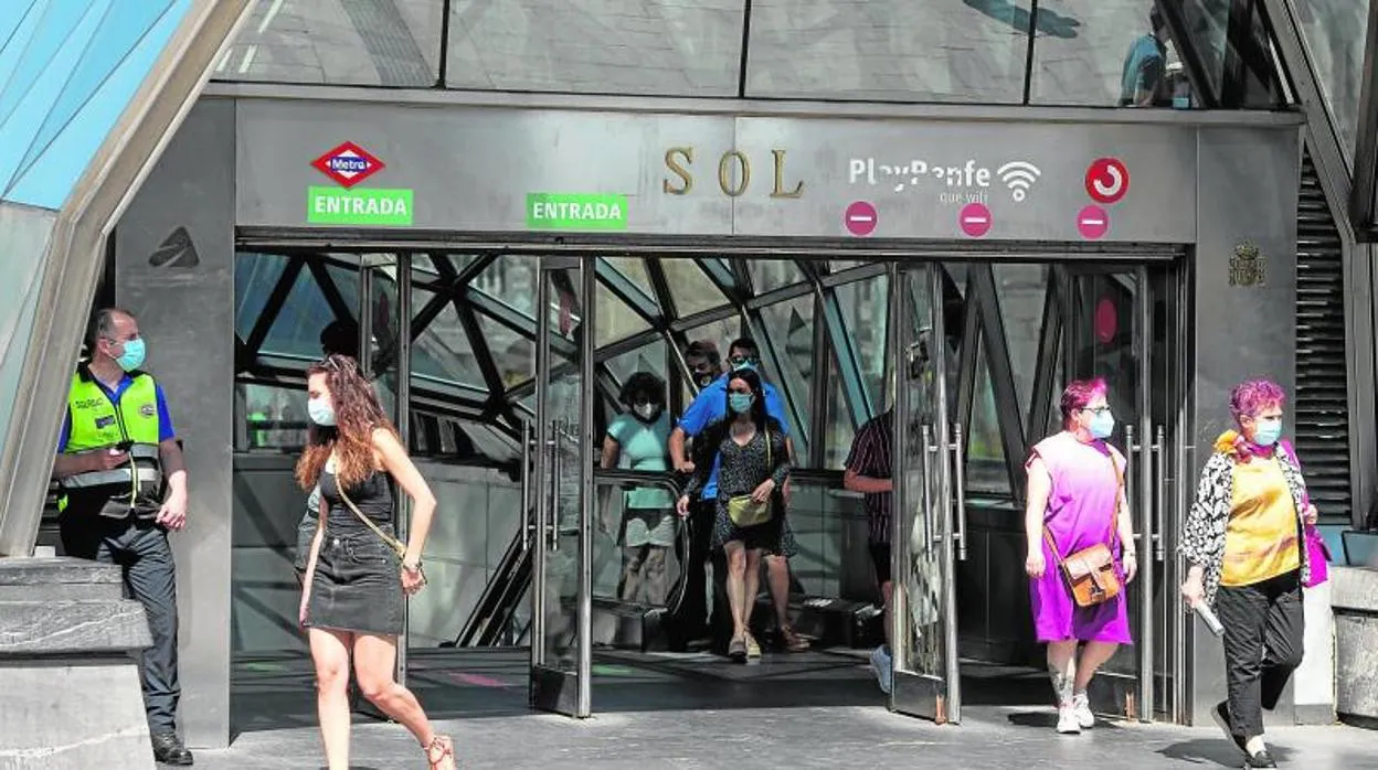 Usuarios del transporte público salen de la estación de Metro y Cercanías de Sol con sus mascarillas puestas