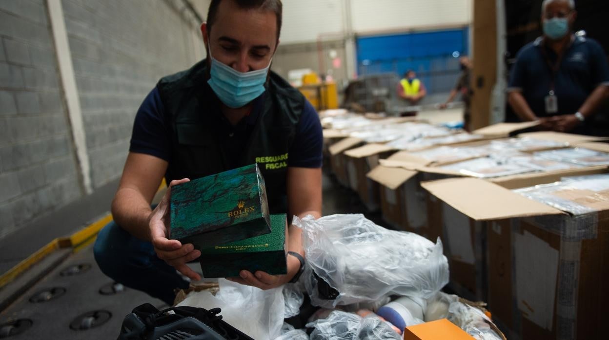 Falsificaciones incautadas. Un agente de la Guardia Civil con un Rolex de imitación, entre un cargamento de zapatillas