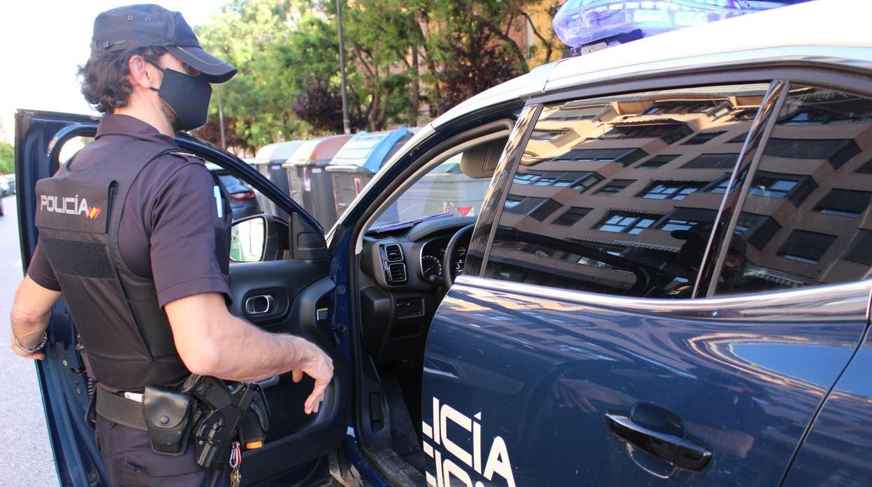 Imagen de recurso de un agente de la Policía Nacional junto a su coche patrulla en Valencia