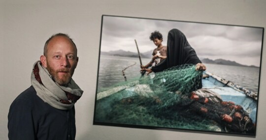 El fotógrafo Pablo Tosco, premiado en el World Press Photo 2021 en la categoría de «Asuntos contemporáneos», posa junto a su fotografía