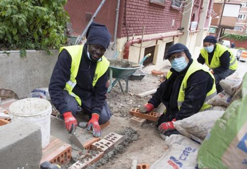 Hamed, sobre estas líneas, trabaja con dos compañeros para construir una escalera en un espacio interbloque de Hortaleza