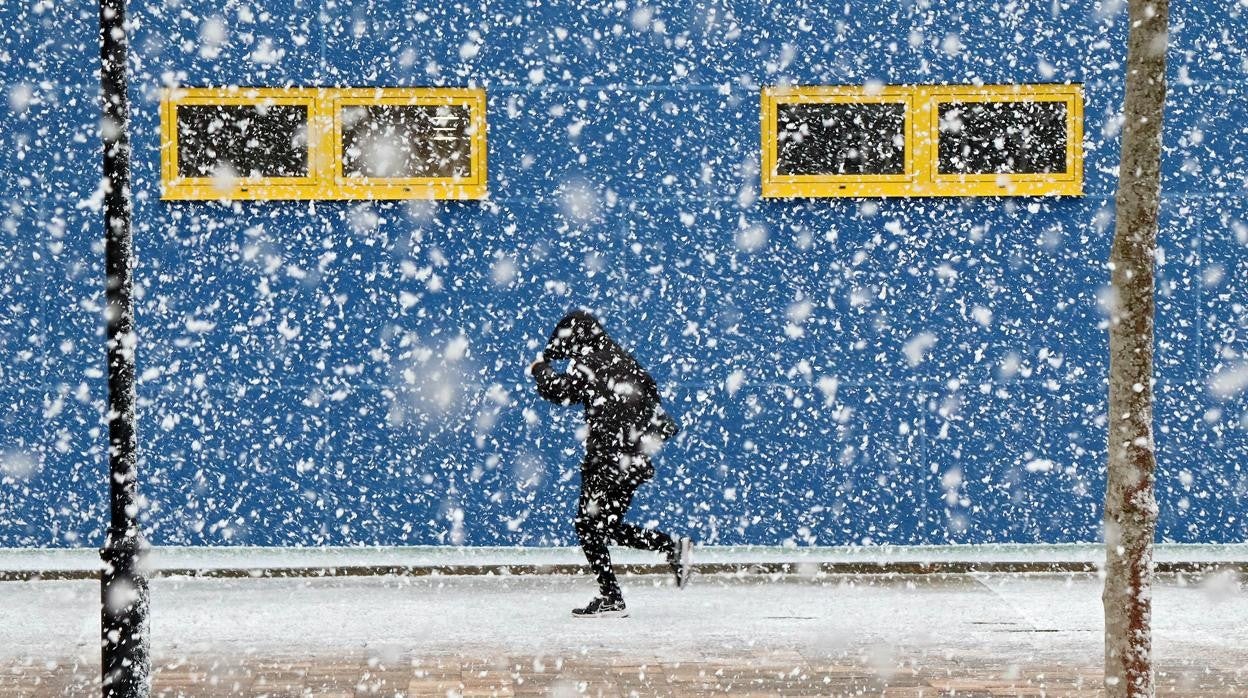 Una persona corre bajo la nevada que arrecia sobre la ciudad de León