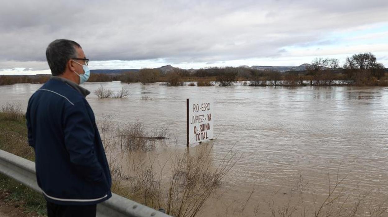 Un lugareño observa con impotencia la inundación del Ebro en tierras de Novillas (Zaragoza). Entre las aguas desbocadas asoma un cartel de protesta reclamando la limpieza del cauce para evitar inundaciones