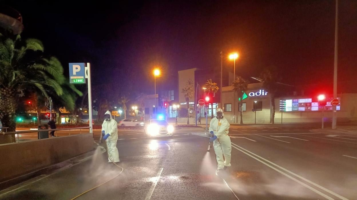 Dos operarios desinfectan la Avenida de la Estación de Alicante