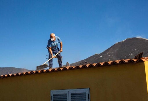 Vecino limpia ceniza en la azotea de su casa en Las Manchas