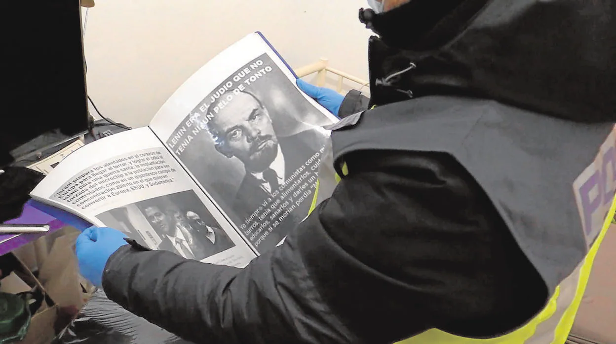 Un policía lee la propaganda encontrada durante el registro