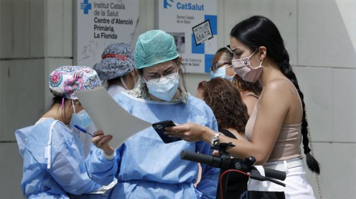 Miembros de un centro de atención primaria, como punto de vacunación, atienden a varios ciudadanos, en Cataluña