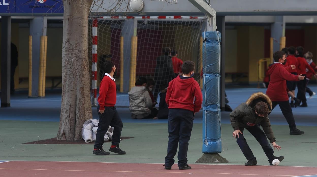 Unos niños juegan en el patio con mascarillas