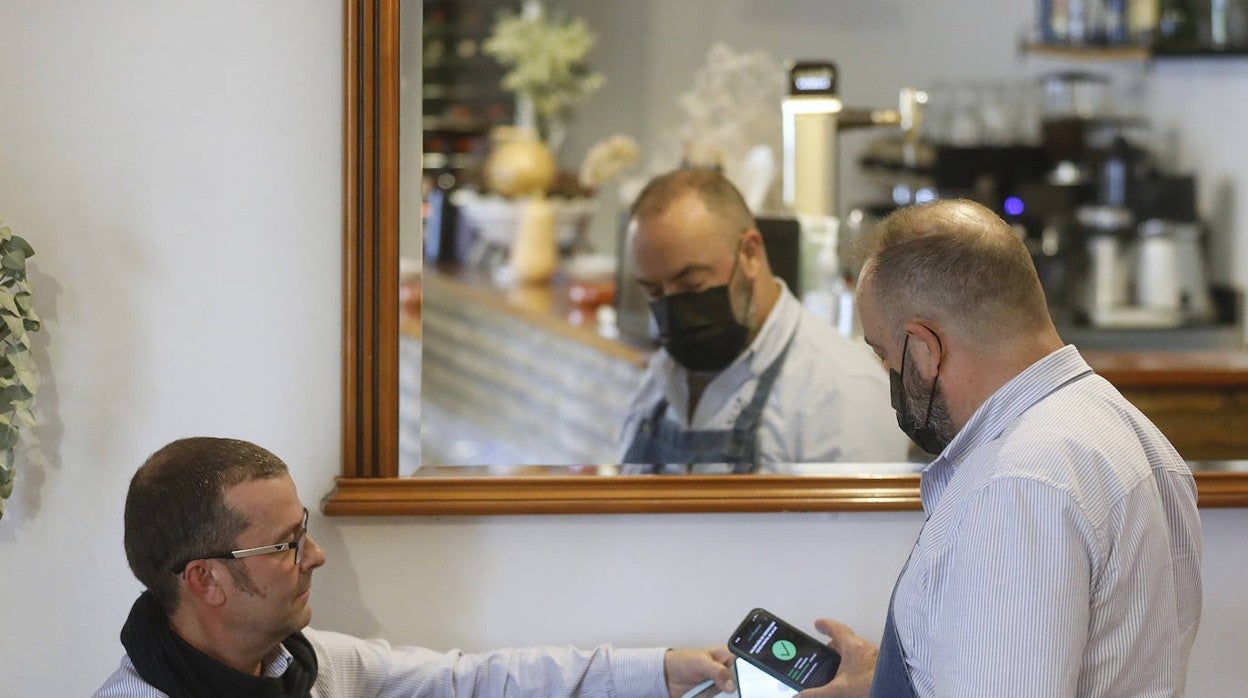 Un cliente muestra su pasaporte Covid en un restaurante