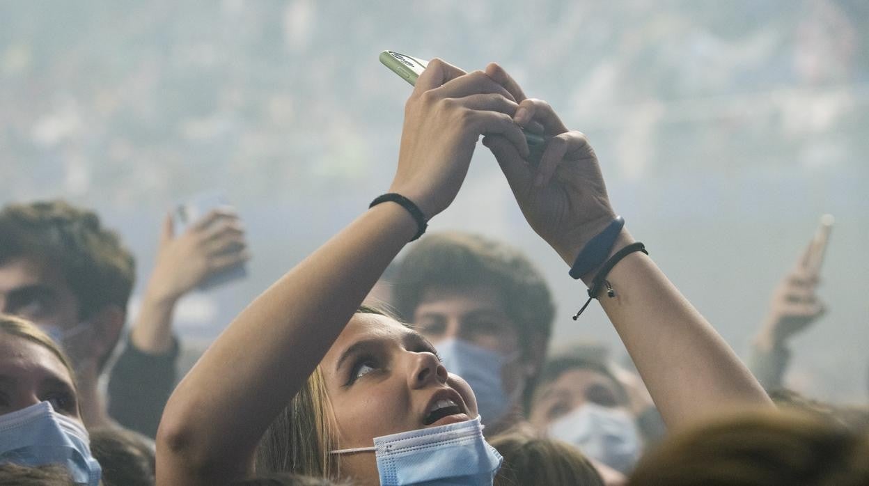 Una joven, con la mascarilla bajada durante un concierto