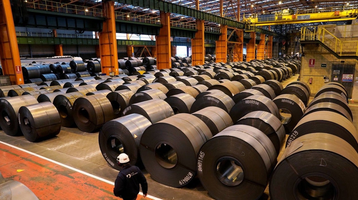 Un trabajador pasa junto a rollos de acero en la planta siderúrgica de ArcelorMittal en Sestao (Vizcaya)