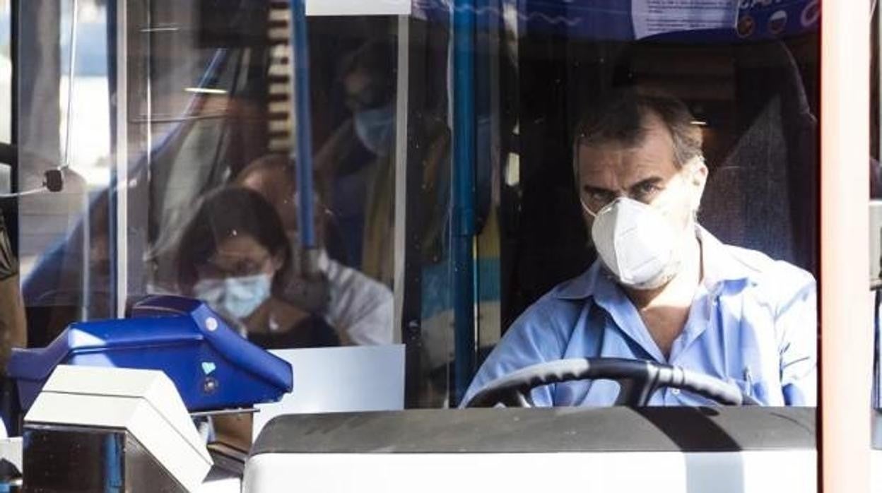 Imagen de un conductor de autobús y un grupo de viajeros con mascarilla