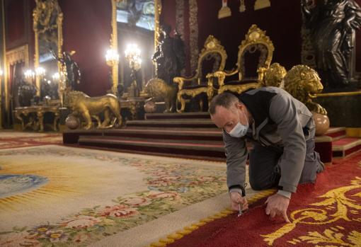 Un tapicero del Palacio Real descose las costuras de la alfombra del salón del trono