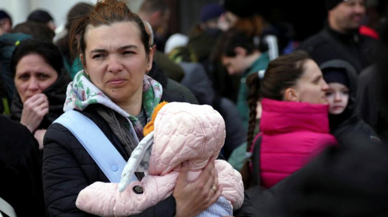 Mujer sostiene a su bebé mientras espera al tren que la evacúe de Odesa