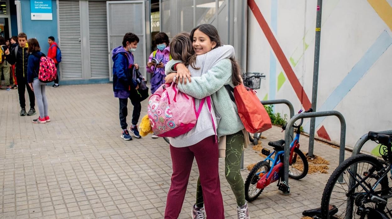 Dos alumnas de una escuela de Barcelona se abrazan en su vuelta al colegio sin mascarilla tras años de restricciones