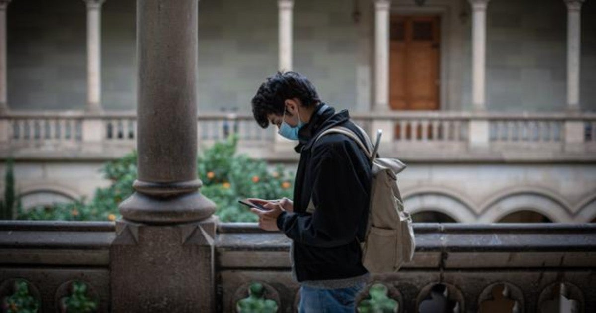 Un alumno consulta su teléfono móvil en el patio central de la Universitat de Barcelona