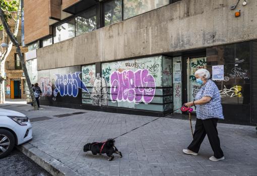 Una mujer pasa frente a unas viejas oficinas del Santander usurpadas