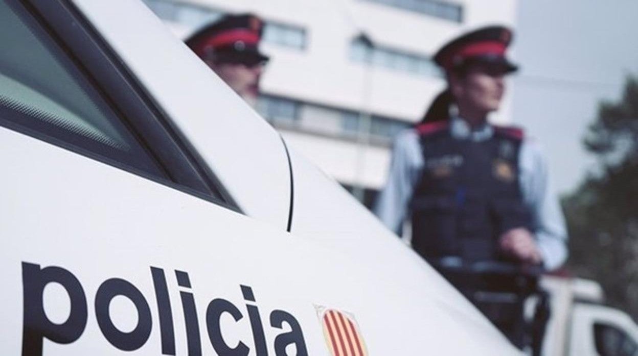 Dos agentes de la Policía catalana junto a un coche patrulla