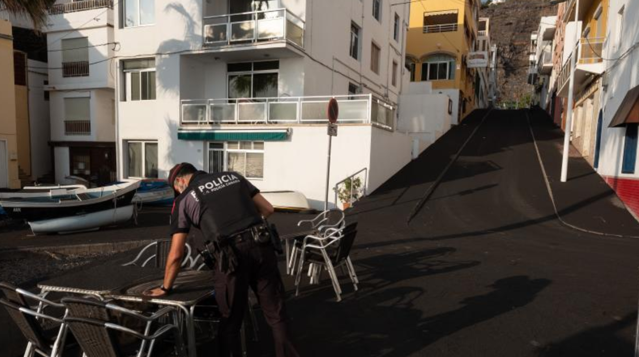 Agente de policía retira ceniza acumulada en Puerto Naos, cerrado por gases