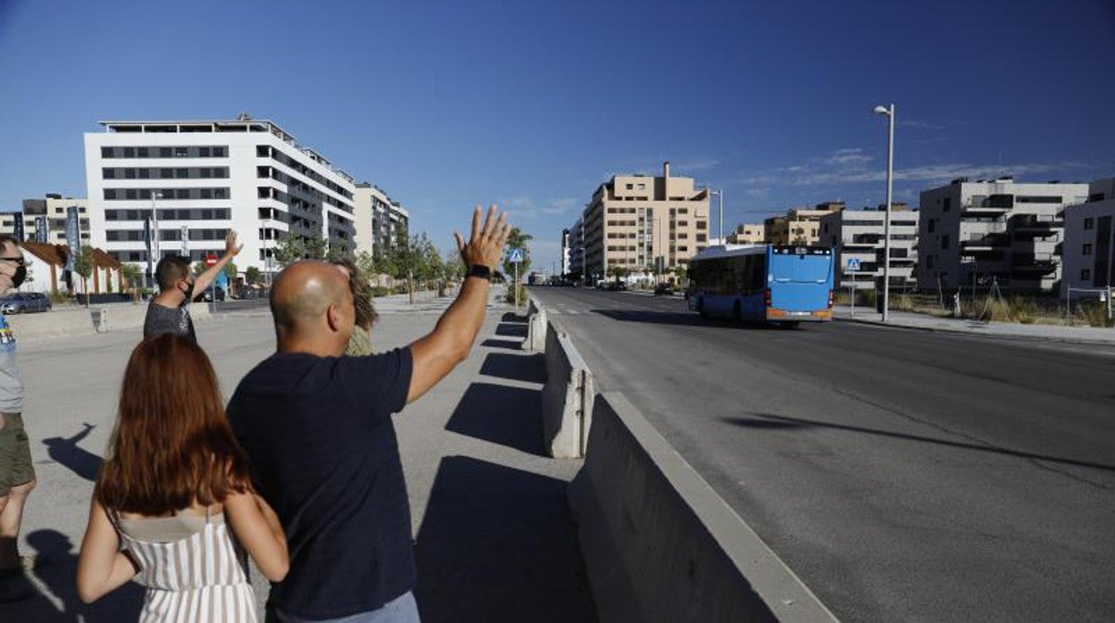 Varios vecinos esperan a uno de los pocos autobuses que conectan el barrio con el resto de la ciudad