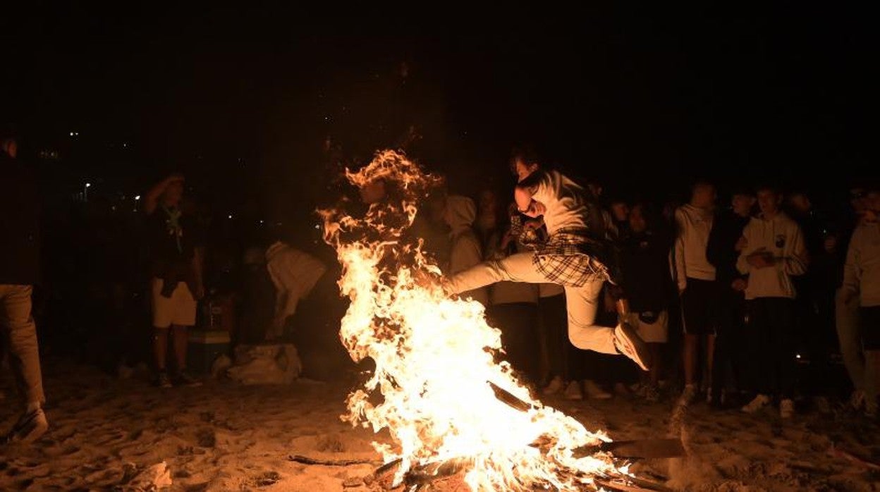 Un joven salta una hoguera en una playa de La Coruña durante la noche de San Juan