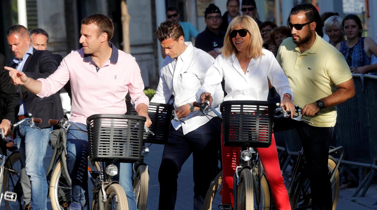 Emmanuel y Brigitte Macron posan para los medios mientras dan un paseo junto a Benalla (amarillo)