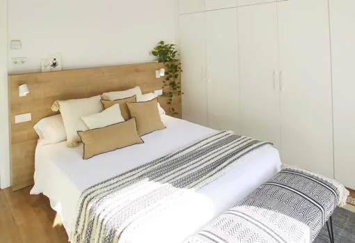 La interiorista Laia Ubia logra un dormitorio principal sencillo, pero muy funcional, donde las mesillas se sustituyen por un cabecero de madera con repisa y apliques integrados