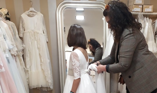 Ana le ata el lazo del vestido de comunión a su hija