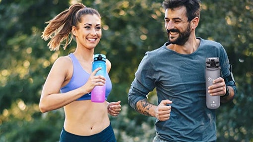 Pareja corriendo con botellas rellenables