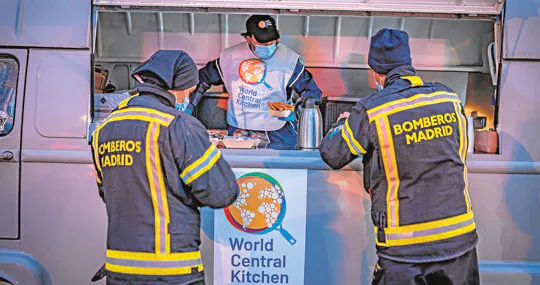 Bomberos del Ayuntamiento de Madrid recogiendo una ración de comida en un puesto de WCK