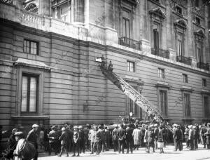 Los bomberos colocando en los muros exteriores del Real Palacio grandes carteles...