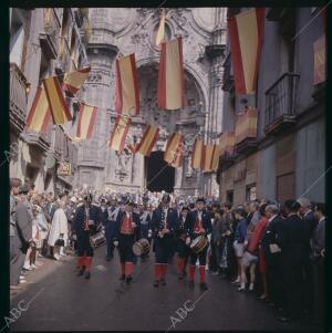 Calle Mayor, decorada con banderas de España, los músicos tocan y los vecinos...