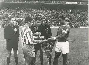 En la imagen, los capitanes de ambos equipos intercambias los banderines