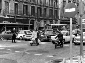 Un policia municipal, con su tradicional casco, dirige el tráfico en la calle de...