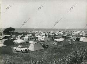 Camping instalado frente a la playa, lleno de tiendas de campaña y automóviles