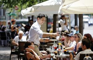 En la imagen, un camarero atiende a una de las mesas de turistas en una terraza...